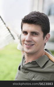 Portrait of young smiling man holding a rake on a roof top garden in the city