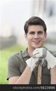 Portrait of young smiling man holding a rake on a roof top garden in the city