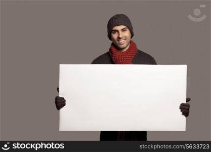 Portrait of young smiling man holding bill board over colored background