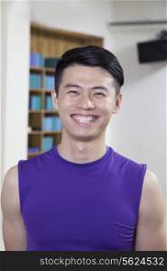 Portrait of young smiling man in a yoga studio, head and shoulders