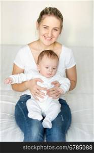 Portrait of young smiling mother sitting with her 3 months old baby