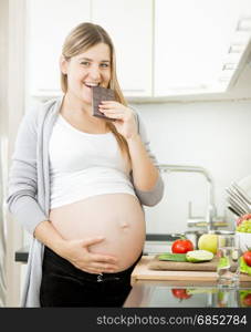 Portrait of young smiling pregnant woman eating chocolate