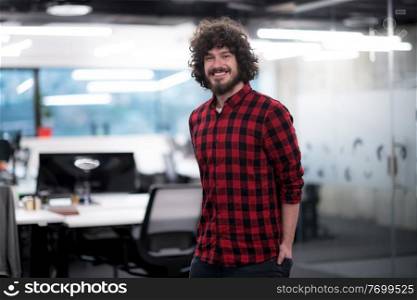 Portrait of young smiling successful male software developer standing at modern startup office