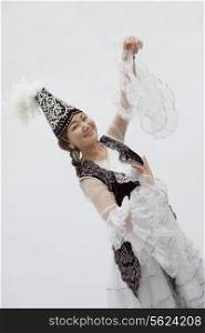 Portrait of young smiling woman dancing in traditional clothing from Kazakhstan, studio shot