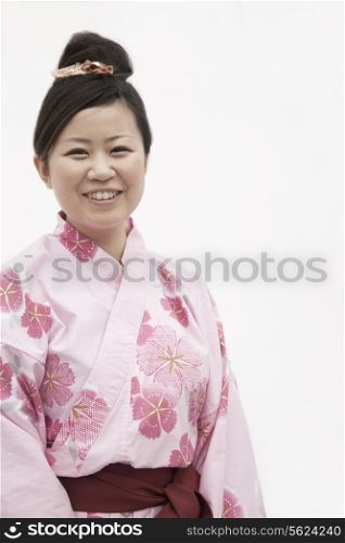 Portrait of young smiling woman in a pink Japanese kimono, studio shot