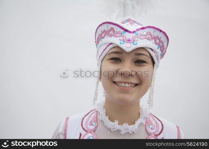 Portrait of young smiling woman in traditional clothing from Kazakhstan, studio shot