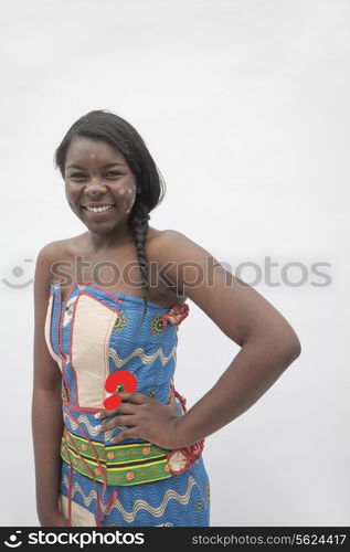 Portrait of young smiling woman with hand on her hip in traditional dress from Africa, studio shot