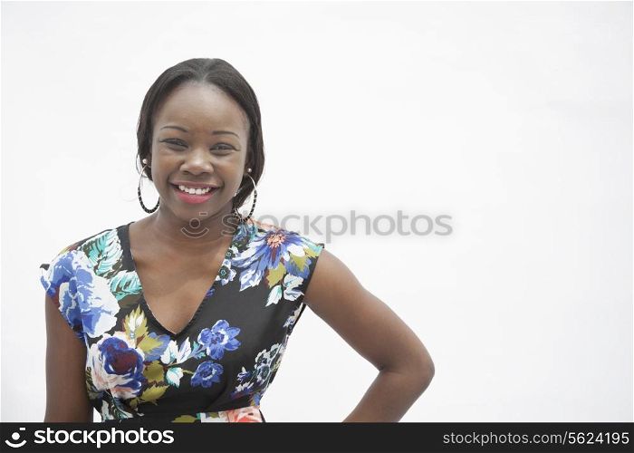 Portrait of young smiling woman with hand on hip in traditional clothing from Africa, studio shot