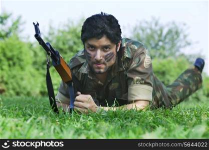 Portrait of young soldier holding gun outdoors
