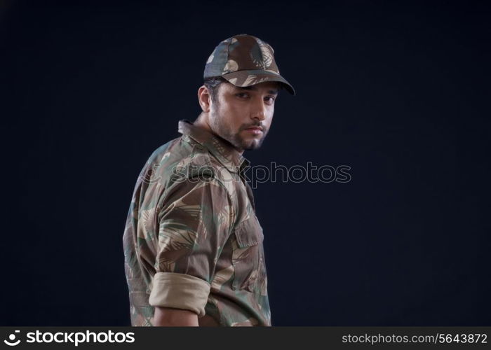 Portrait of young soldier standing over black background