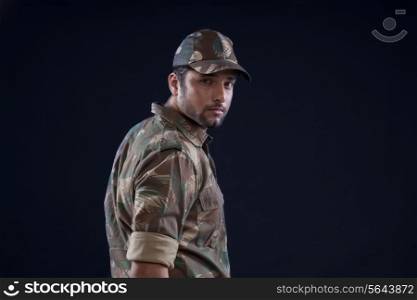 Portrait of young soldier standing over black background