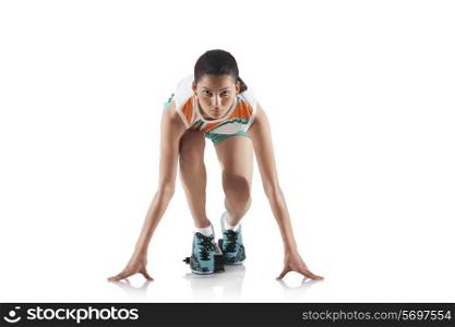 Portrait of young sporty woman at starting block of race isolated over white background