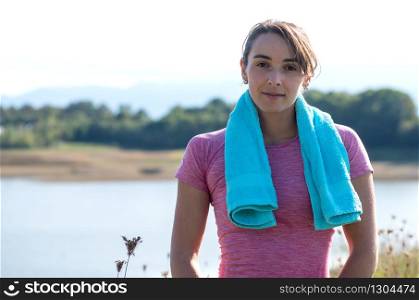 portrait of young sporty woman with blue towel in the countryside
