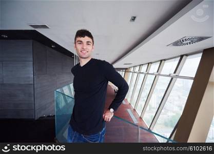 portrait of young successful startup business man in penthouse, modern bright duplex office apartment interior with staircase and big windows