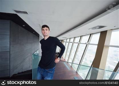 portrait of young successful startup business man in penthouse, modern bright duplex office apartment interior with staircase and big windows