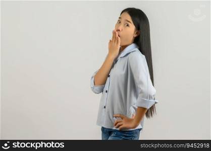 Portrait of Young surprised asian woman in blue shirt puts her hand over her mouth isolated on white background. Expression and lifestyle concept.