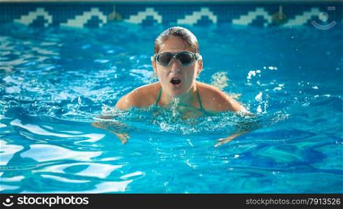 Portrait of young swimmer woman taking a breath at swimming pool