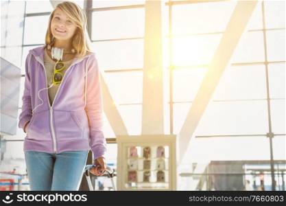 Portrait of young teenage girl walking with her suitcase in airport