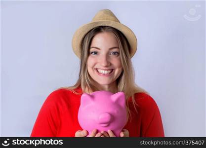 Portrait of young tourist woman holding a piggy bank on studio. Save money and travel concept.