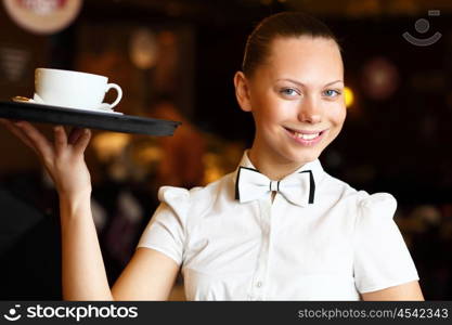 Portrait of young waitress in white blouse holding a tray