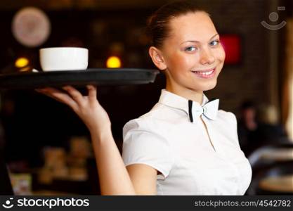 Portrait of young waitress in white blouse holding a tray