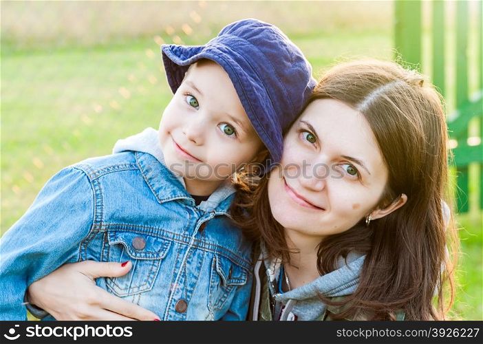 portrait of young woman and boy mother and son family in summer sunshine over green