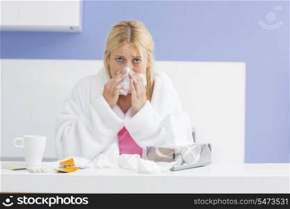 Portrait of young woman blowing nose in tissue paper