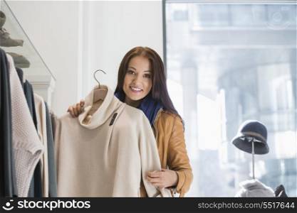 Portrait of young woman choosing sweater in store