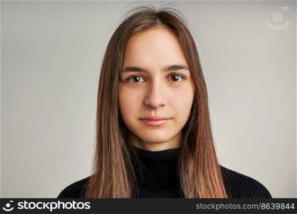 Portrait of young woman. Classic portrait in positive mood, beautiful model posing in studio over plain background looking at camera