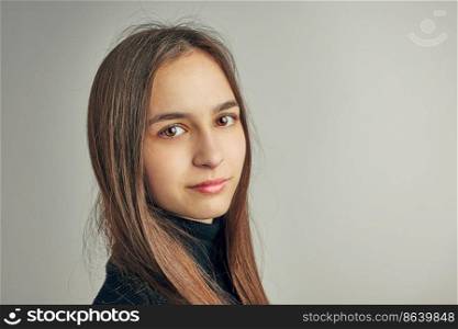 Portrait of young woman. Classic portrait in positive mood, beautiful model posing in studio over plain background looking at camera