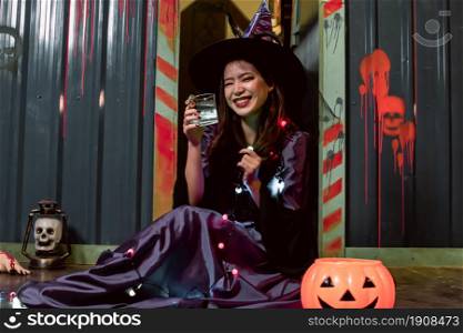 Portrait of young woman dressing halloween witch costume while sitting in party