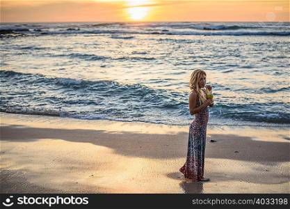 Portrait of young woman drinking cocktail on beach at sunset, Tamarindo, Costa Rica