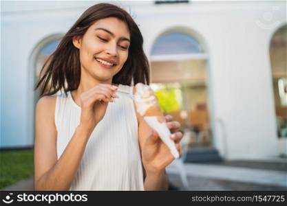 Portrait of young woman enjoying sunny weather while eating an ice cream outdoors. Lifestyle concept.