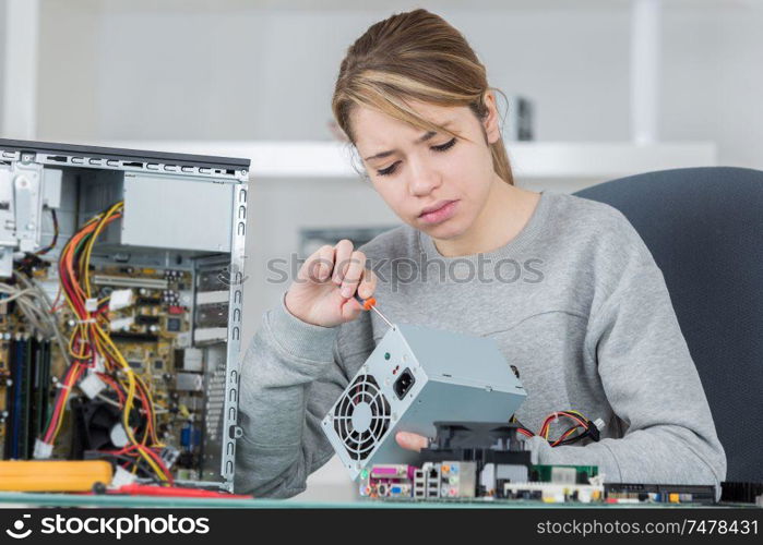 portrait of young woman fixing computer