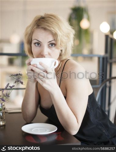 Portrait of young woman having coffee at restaurant table