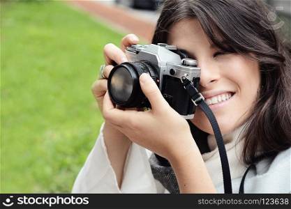 portrait of young woman having fun taking photos with retro film camera. Outdoor lifestyle portrait.