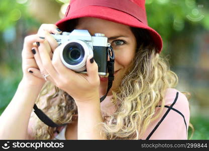 portrait of young woman having fun taking photos with retro film camera. Outdoor lifestyle portrait.