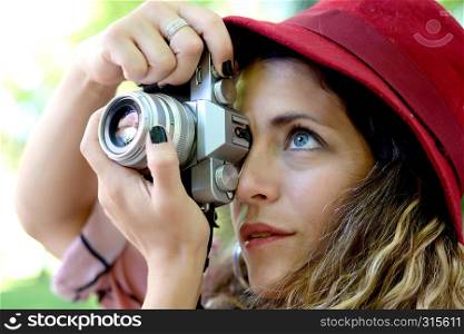 portrait of young woman having fun taking photos with retro film camera. Outdoor lifestyle portrait.