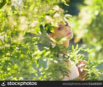 Portrait of young woman hiding in foliage
