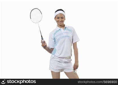 Portrait of young woman holding badminton racket and shuttlecock isolated over gray background