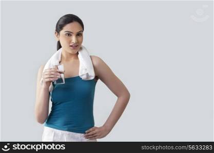 Portrait of young woman holding glass of water isolated over gray background
