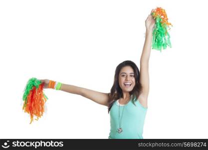 Portrait of young woman holding out tricolor pom poms over white background