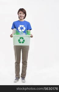 Portrait of young woman holding recycling bin, studio shot