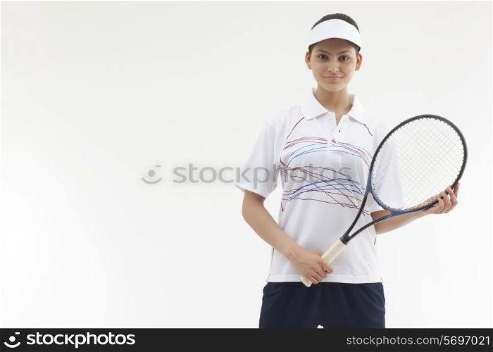 Portrait of young woman holding tennis racket isolated over gray background