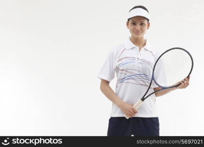 Portrait of young woman holding tennis racket isolated over gray background
