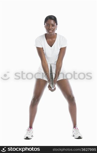 Portrait of young woman holding tennis racket standing over white background