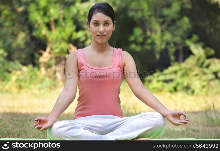 Portrait of young woman in lawn sitting in lotus position