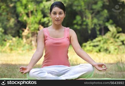Portrait of young woman in lawn sitting in lotus position