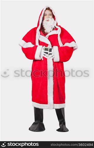 Portrait of young woman in Santa costume standing against gray background