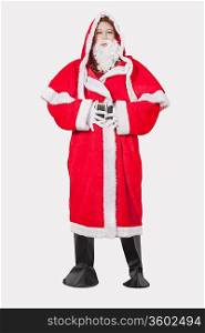 Portrait of young woman in Santa costume standing against gray background